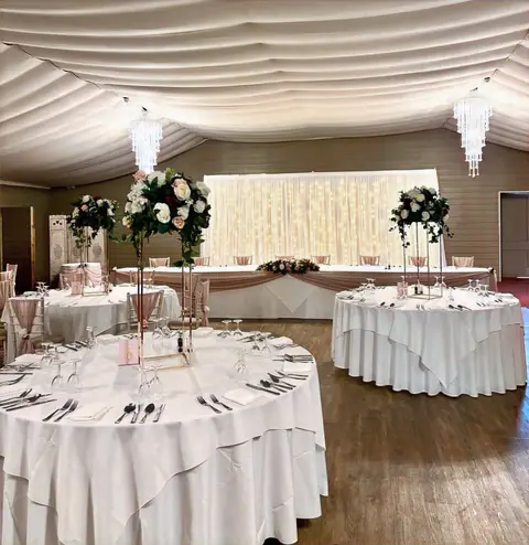 Wedding breakfast room with tall floral centrepieces and a starlit backdrop