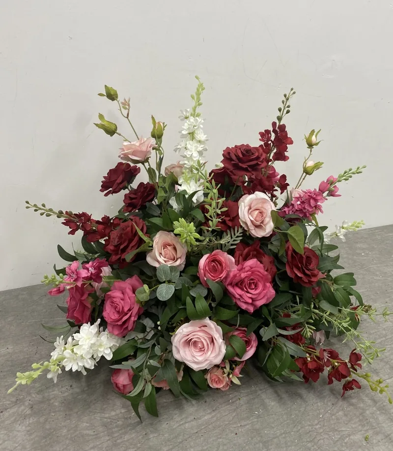 Large centrepiece of deep red and pink roses with greenery