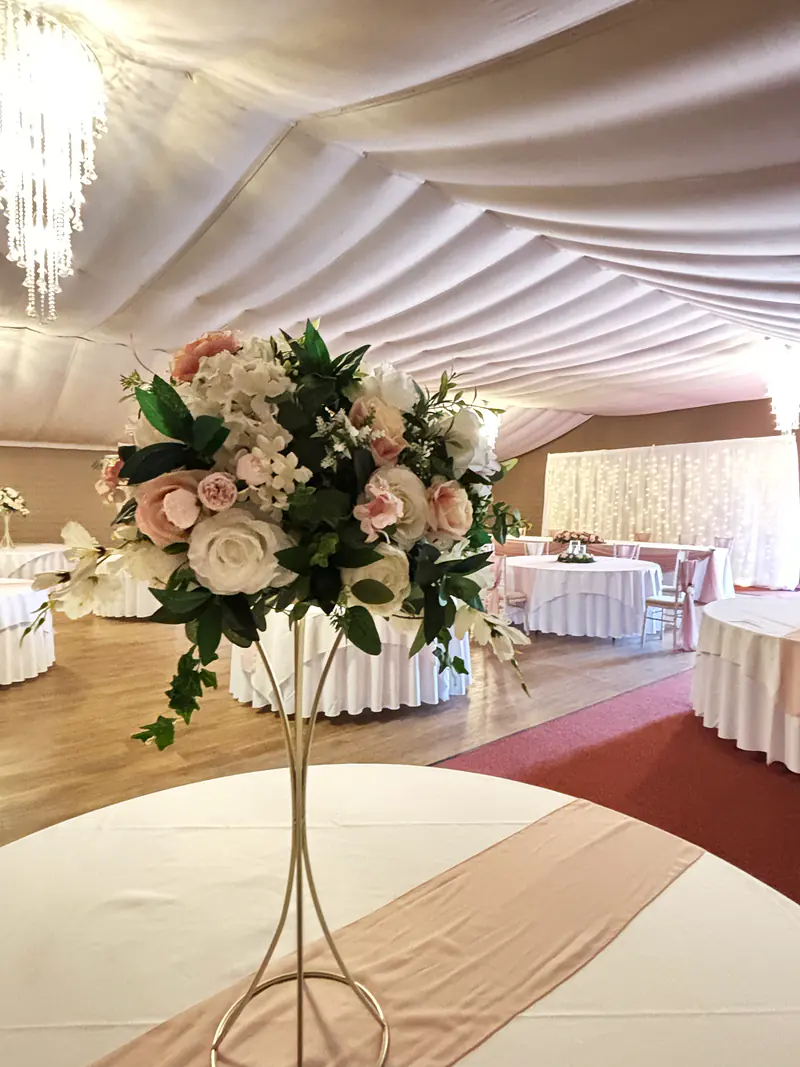 Ivory and pale pink floral centrepiece on a gold trumpet stand