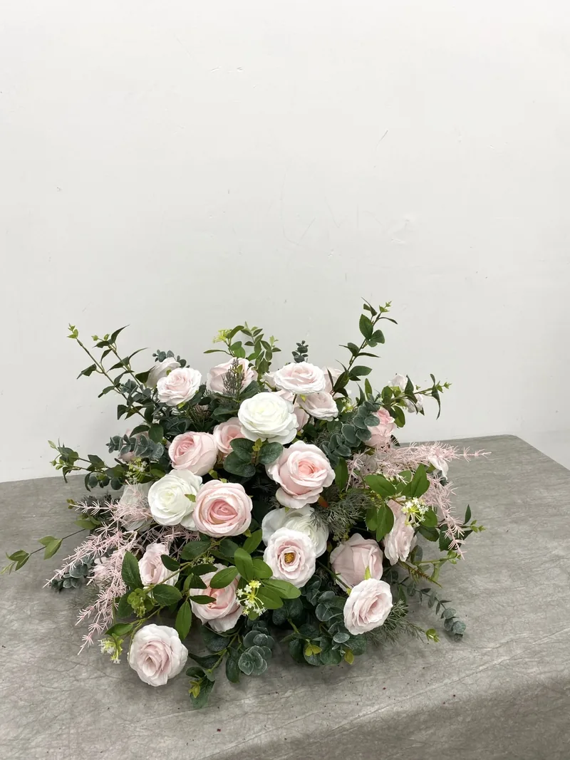 Low centrepiece of pale pink and ivory roses with greenery