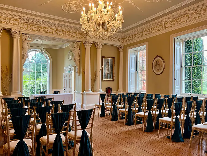 Ceremony chairs with dark green chiffon drapes in a country house