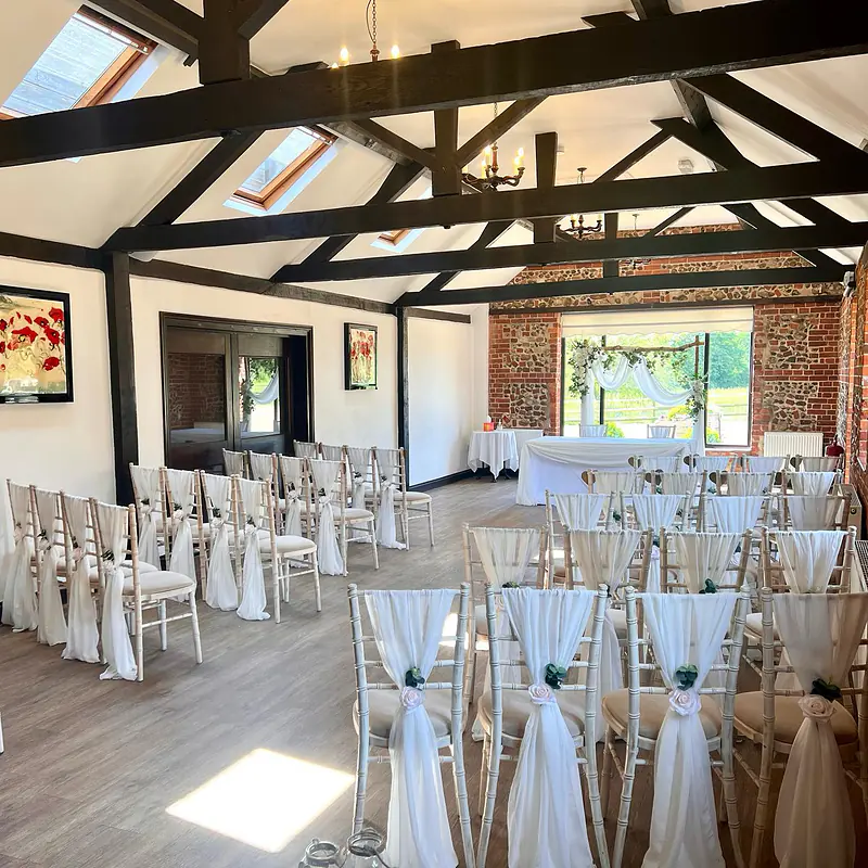 Ceremony room with ivory chiffon chair drapes finished with ivory roses and sprigs of eucalyptus