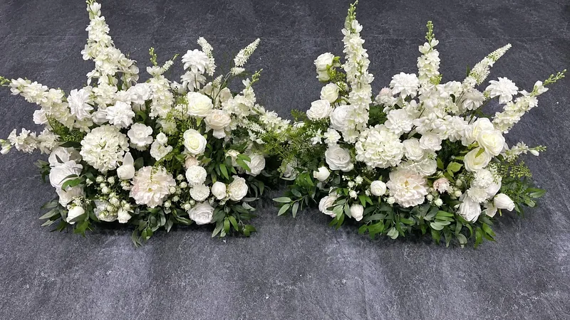 Two floor-standing arrangements of ivory flowers and greenery