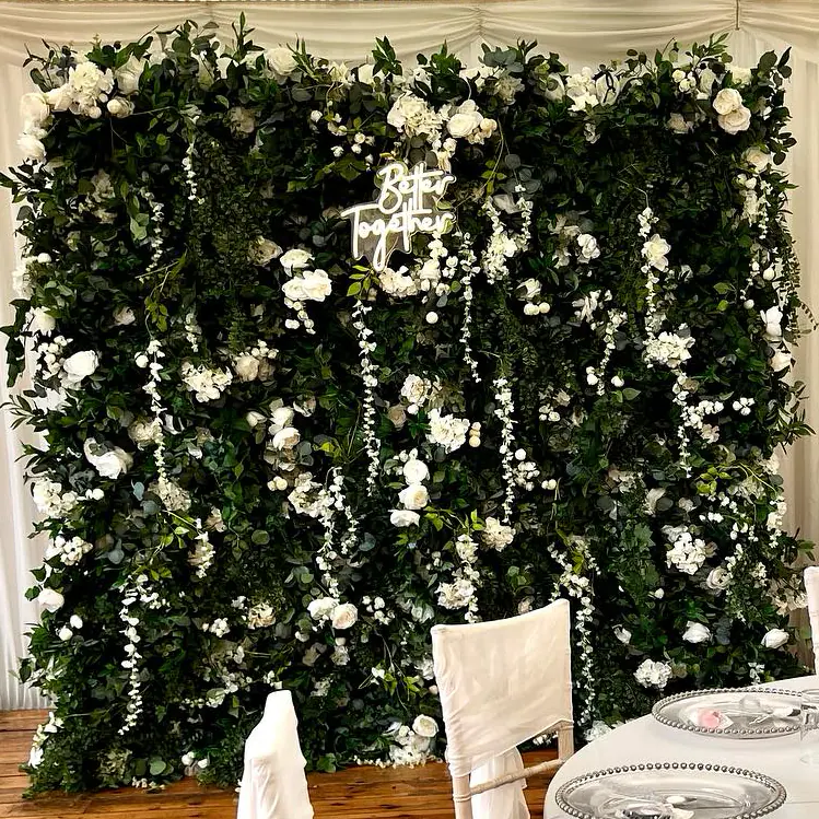 Close-up of the flower wall’s greenery, ivory flowers and neon sign