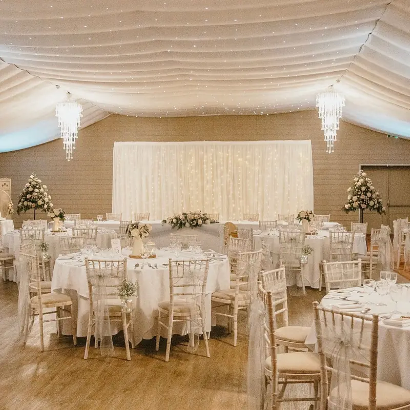 Wedding breakfast room with a starlit backdrop and ivory chair sashes