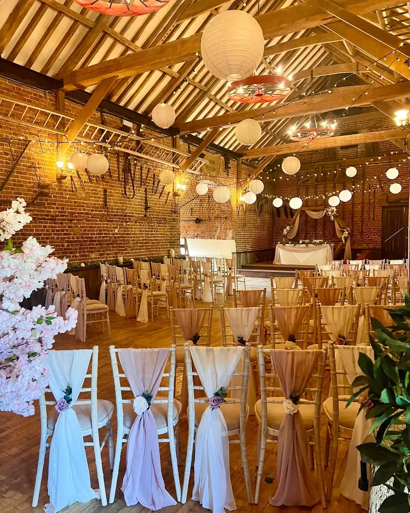 Barn reception with dressed chairs and paper lanterns
