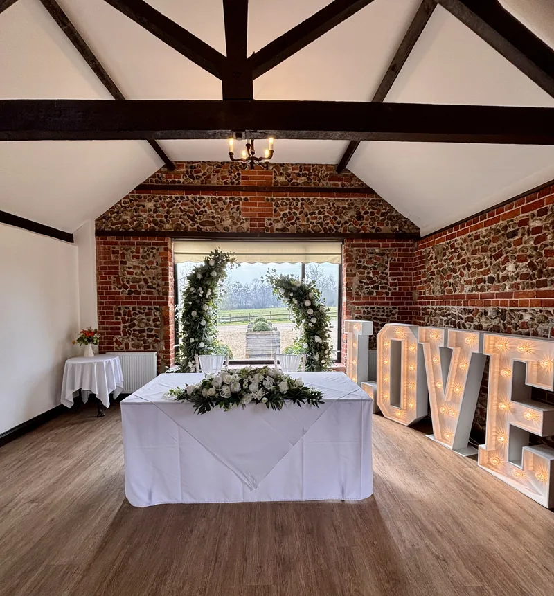 Broken greenery arch behind a ceremony table in the Park Room at Hunters Hall, beside light-up LOVE letters