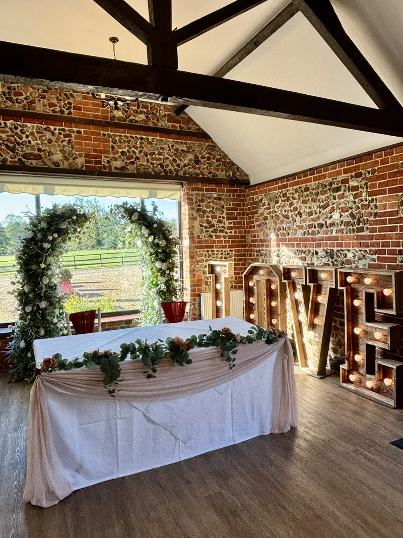 Broken greenery arch at a window behind a table with a pale pink swag and greenery garland