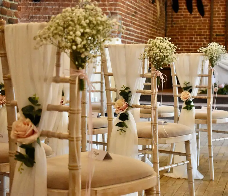 Chiavari chairs dressed with ivory chiffon drapes, roses and gypsophila