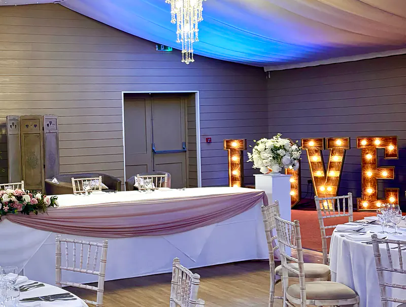 Rustic LOVE letters lit up beside the top table in a reception room