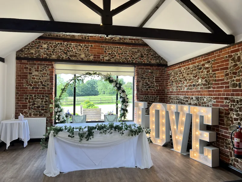 Greenery moon gate and white light-up LOVE letters behind a ceremony table in the Park Room at Hunters Hall