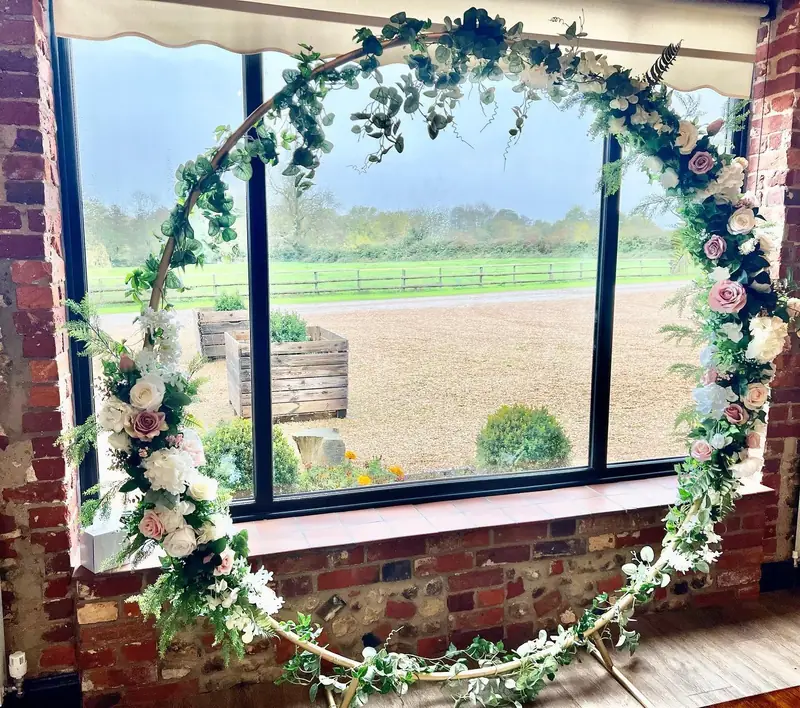 Moon gate decorated with greenery and ivory and pale pink flowers