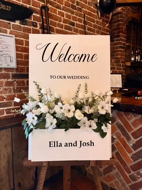 White personalised welcome sign with a box of ivory flowers