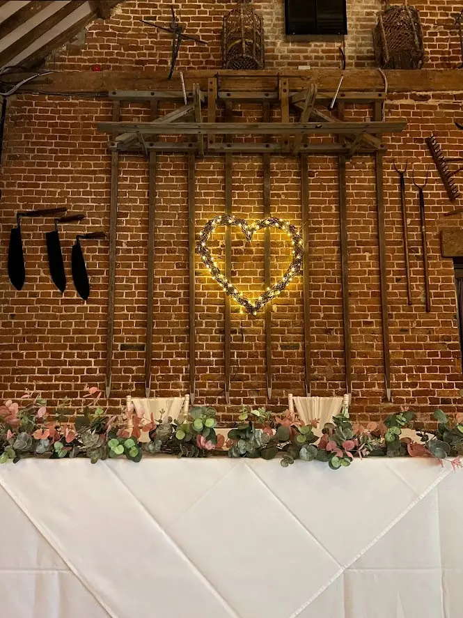 Top table with a eucalyptus garland beneath a lit willow heart