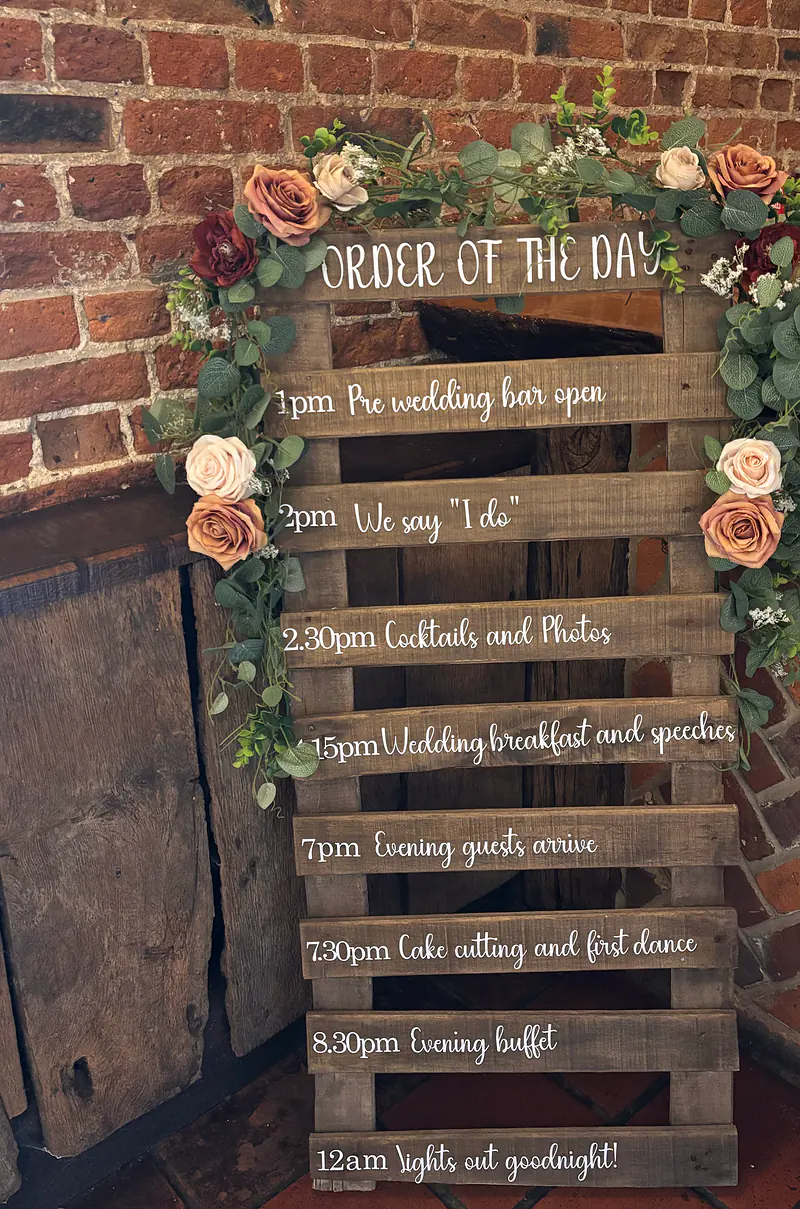 Rustic wooden order of the day sign dressed with roses and eucalyptus