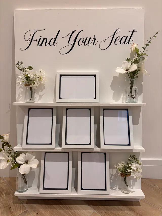 White table plan with frames for seating cards and bud vases of ivory flowers