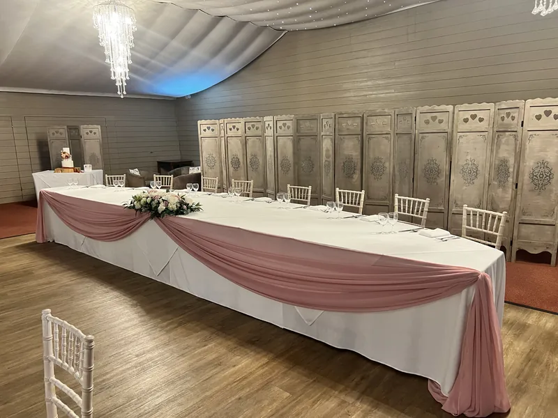 Long top table dressed with a rose pink chiffon swag