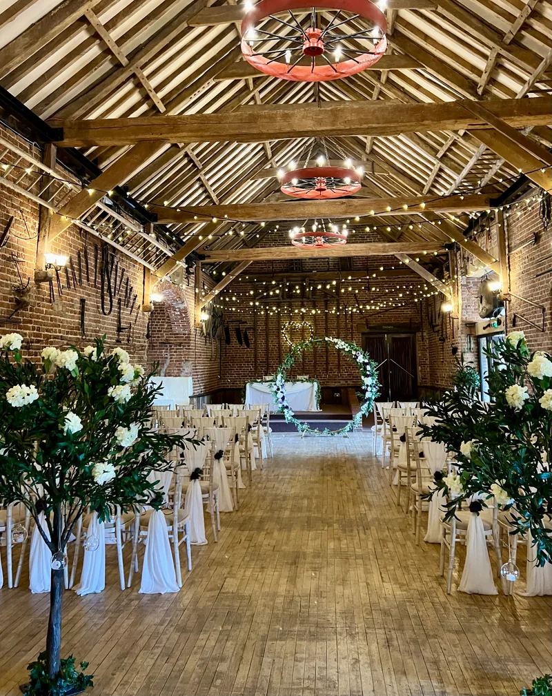 Greenery trees with ivory blossoms along the aisle of a barn ceremony