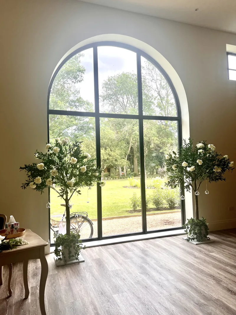 Greenery trees with ivory blossoms either side of a tall arched window