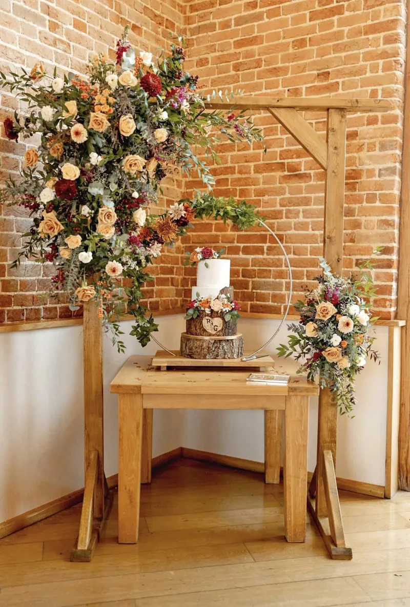 Rustic wooden arch with a florist’s flowers behind a cake table