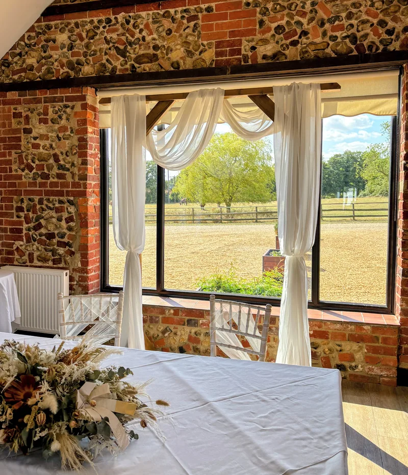 Rustic wooden arch dressed with ivory chiffon drapes in front of a window
